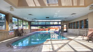 An indoor swimming pool with clear glass walls, a lifeguard chair, and a warning sign. - Studio Premier Condo | Ski-in/Skit-out Access (Breckenridge)