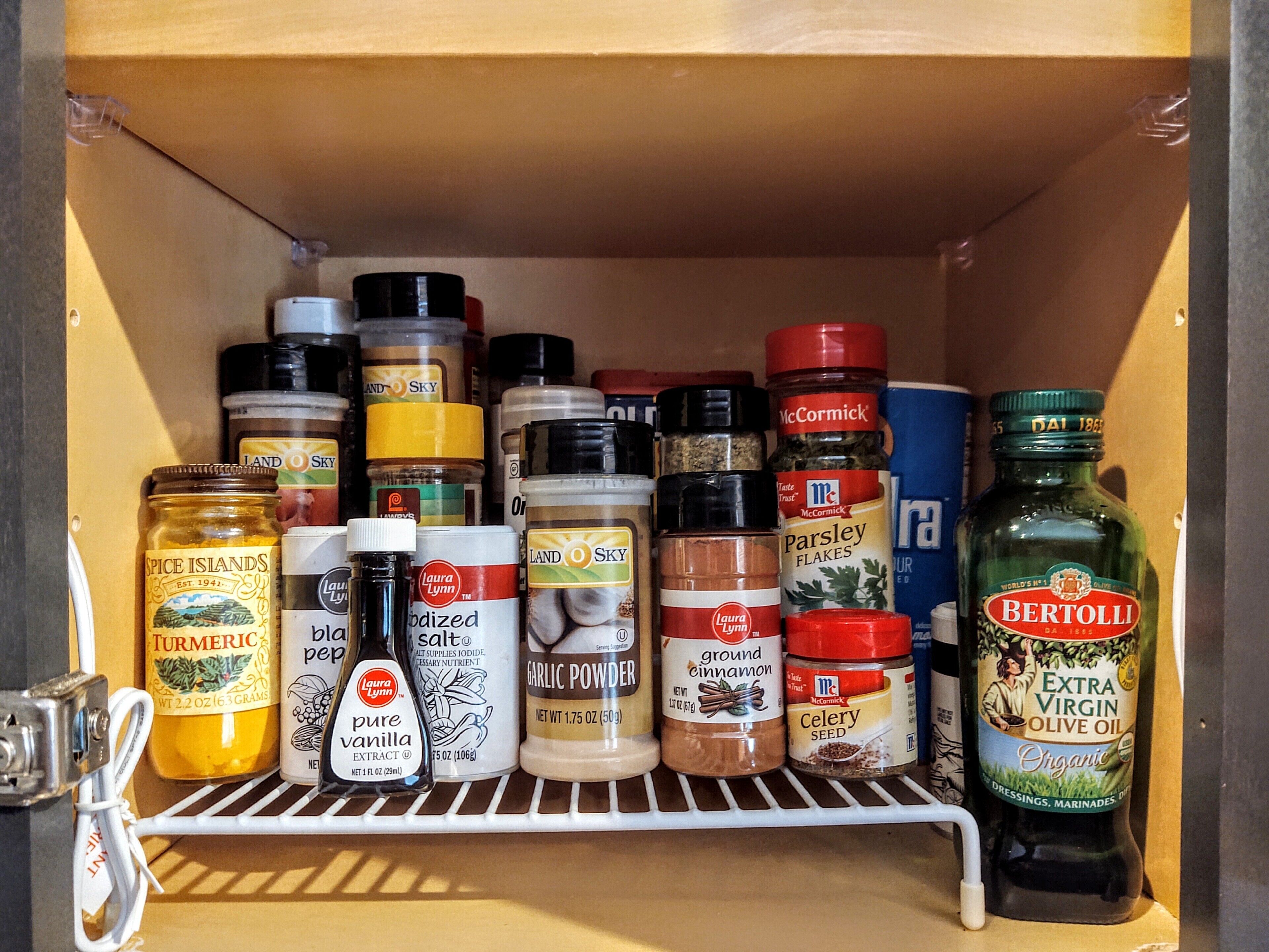 Eine Gewürzleiste mit verschiedenen Gewürzen und einer Flasche natives Olivenöl extra.