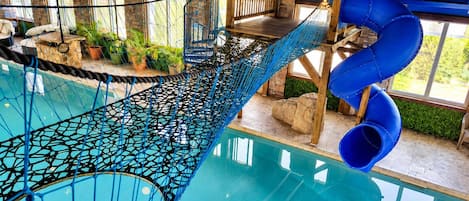 A pool area with a rope bridge, slides, and wooden structures.