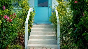 A cottage with a turquoise door and a sign reading "Sanctuary Cottage." - The ONLY house with POOL for rent in Spanish Wells! Five star service. (Spanish Wells)