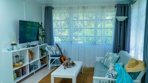 A living room with a TV, bookshelf, and a sofa with a hat. - The ONLY house with POOL for rent in Spanish Wells! Five star service. (Spanish Wells)
