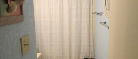 Ein kleines Badezimmer mit Toilette, Duschvorhang und Mülleimer.