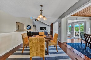 A dining area with a wooden table, four woven chairs, a chandelier, and a view of the outdoors. - Summer Lane NO WAKE Cove/FLAT Lot/FirePit/Boats/Hot Tub/Gamerm/Cabana/Generator (Huddleston)