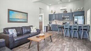Una cocina moderna con armarios grises, un refrigerador de acero inoxidable y una zona de comedor con taburetes de bar.