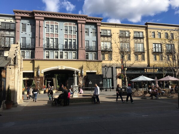 Una plaza pública con una fuente, gente caminando y un edificio con un cartel que dice "Z GALLERY".