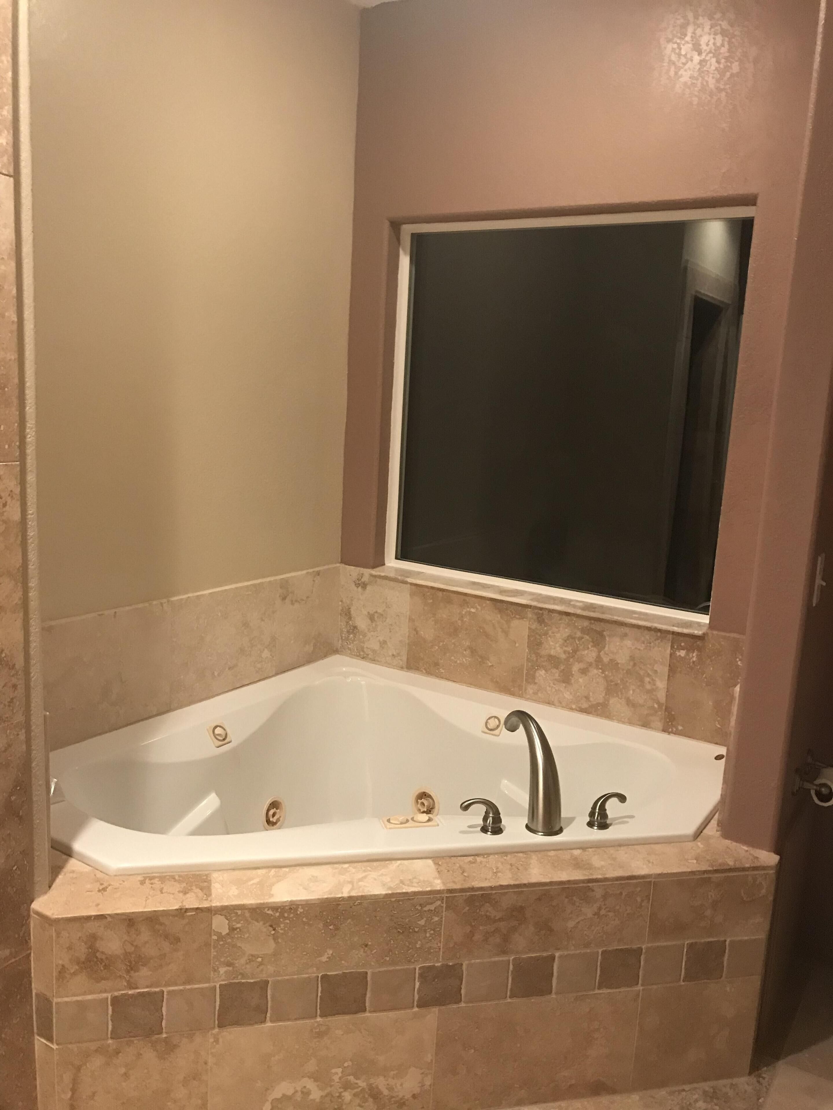A bathroom with a freestanding bathtub, a large mirror above it, and tiled walls.
