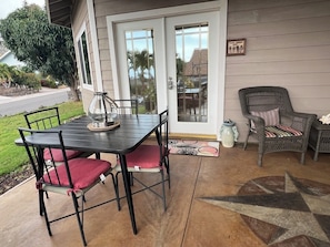 A patio with a table and chairs, a wicker chair, and a decorative vase.