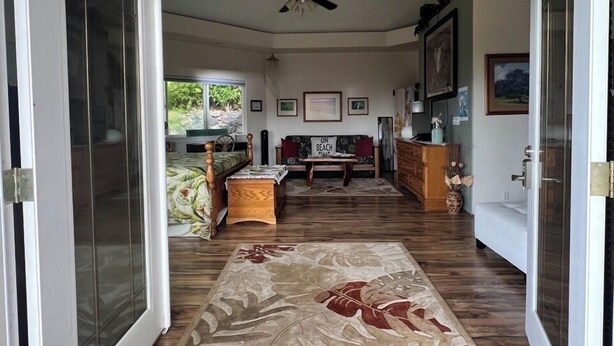 An open door leading to a living room with a ceiling fan, a sofa, a coffee table, and a rug with a leaf pattern. - SUPER SPACIOUS! Privacy entrance. Comfortable and cozy. Quiet and peaceful! (Waikoloa Village)