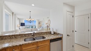A kitchen with granite countertops, a dishwasher, and a view of the living area. - Summer Salt -Beautiful Condo- spectacular views (Navarre)