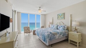 A bedroom with a bed, a TV, a chair, a nightstand, and a view of the ocean. - Summer Salt -Beautiful Condo- spectacular views (Navarre)