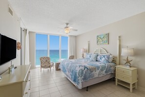 A bedroom with a bed, a TV, a chair, a nightstand, and a view of the ocean. - Summer Salt -Beautiful Condo- spectacular views (Navarre)