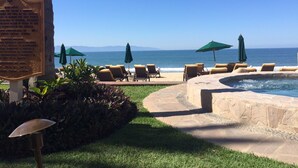 A poolside area with lounge chairs and umbrellas, a signboard, and a view of the ocean.