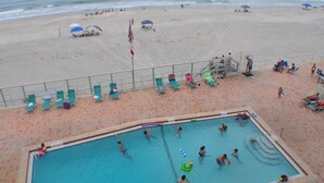A pool area with a lifeguard tower, lounge chairs, and a flagpole. - Direct Oceanfront, Newly Renovated 2-Bedroom, 2-Bath Condo - No Drive Beach (Daytona Beach Shores)