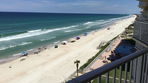 A beach view from a balcony with a pool, umbrellas, and lounge chairs. - Direct Oceanfront, Newly Renovated 2-Bedroom, 2-Bath Condo - No Drive Beach (Daytona Beach Shores)