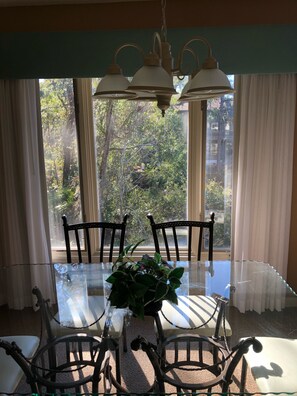 Enjoy meals in this dining area with a glass-top table and four chairs, surrounded by a serene outdoor view.