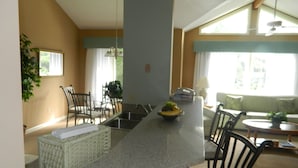 A kitchen with a granite countertop, a sink, and a dining area with chairs and a table. - Brigantine Quarters, Shipyard. Unit 292. 2BD/1.5Ba (Hilton Head Island)