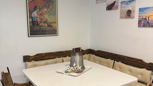 Un comedor con una mesa redonda, sillas acolchadas, un centro de mesa decorativo con una campana y obras de arte en las paredes.