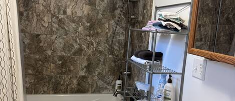 Un baño con ducha, inodoro, lavamanos y un perchero para toallas.