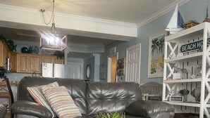 Una sala de estar con un sofá de cuero oscuro, una mesa de centro de madera y una estantería con objetos decorativos.