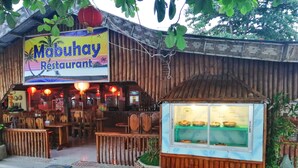 A restaurant with a signboard, wooden exterior, and a display case with food items. - Mabuhay Thresher Dive (Daanbantayan)