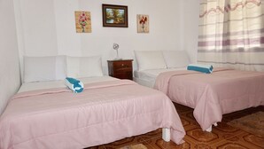A hotel room with two beds, each with a pink bedspread and white pillows. There is a small wooden nightstand with a lamp, and wall art depicting flowers and landscapes. - Mabuhay Thresher Dive (Daanbantayan)