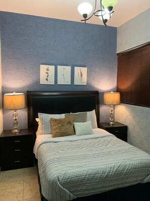 A bedroom with a bed, two bedside tables, a headboard, and wall-mounted artwork. - Franks House (Cancun)