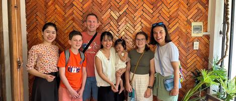 A group of people standing in front of a wooden herringbone-patterned wall.