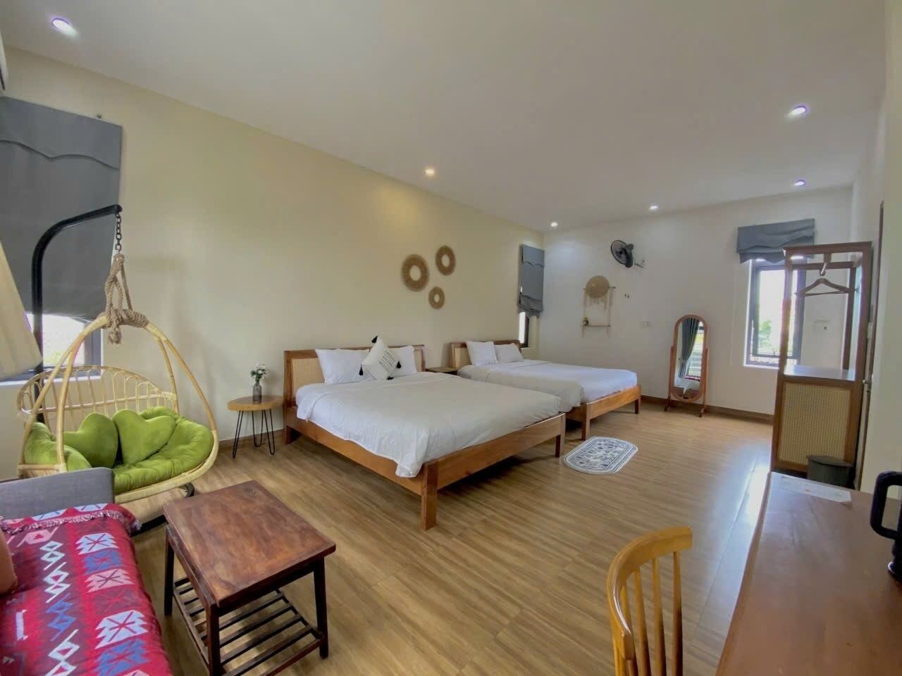 A bedroom with two beds, a hanging chair, a small table, and a chair.