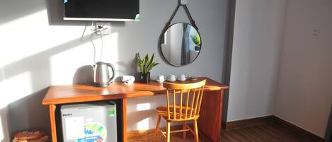 A compact kitchenette with a refrigerator, a coffee maker, and a small plant.