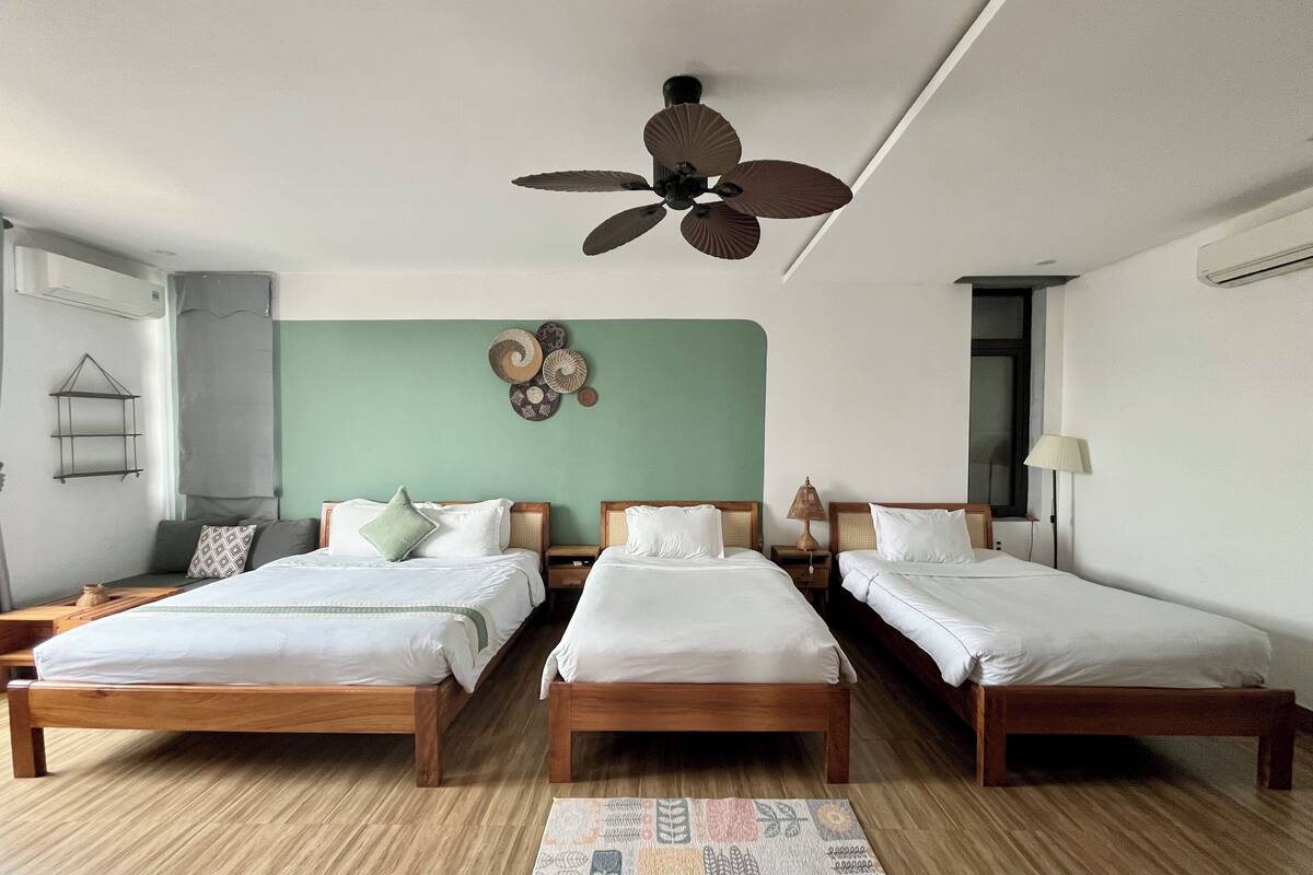 A hotel room with two wooden beds, a ceiling fan, a wall-mounted shelf, and a floor lamp.