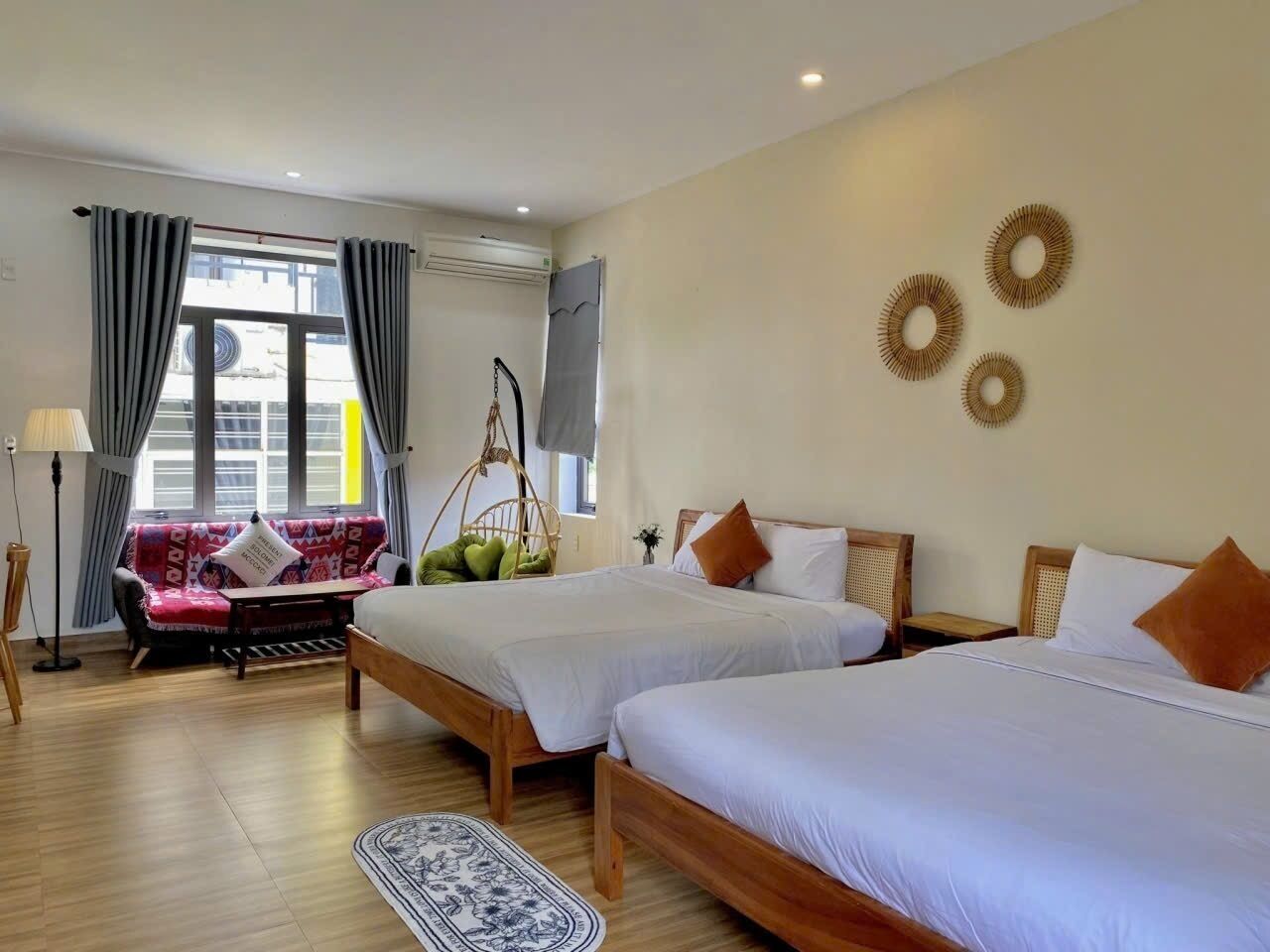 Ein Hotelzimmer mit zwei Betten, einem Schlafsofa, einem Hängesessel und Blick auf die Stadt.