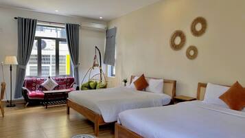 Ein Hotelzimmer mit zwei Betten, einem Schlafsofa, einem Hängesessel und Blick auf die Stadt.