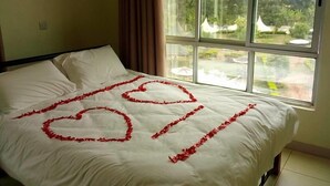 Una cama con sábanas blancas y decoraciones con forma de corazón rojo.