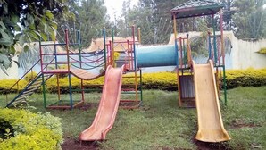 Un parque infantil con dos toboganes, una estructura de escalada y una zona cubierta.