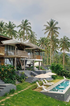 A resort with a pool, lounge chairs, and a staircase leading to a deck. - Bintana Sa Paraiso Binunsaran (Mambajao)