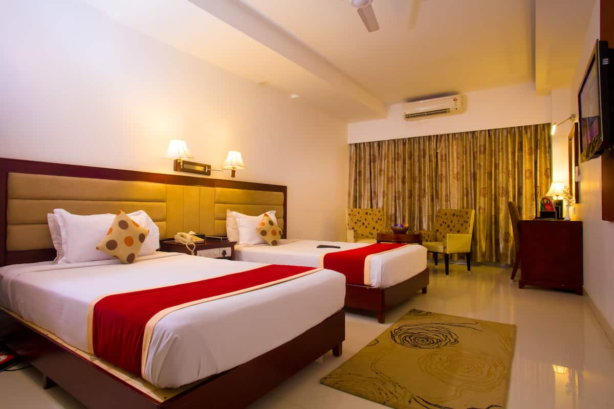A hotel room with two beds, a desk, a chair, a TV, and a window with curtains.