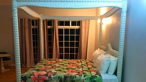 Un lit à baldaquin avec une couvre-lit à motifs floraux, une table de chevet et des rideaux.