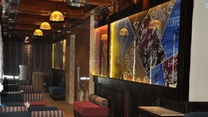 A cozy lounge area with plush seating, a fireplace, and a large coffee-themed wall mural. - Hotel Southgate Shimla (Shimla)