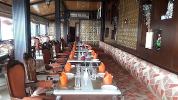 A restaurant with long tables, orange napkins, and patterned walls.