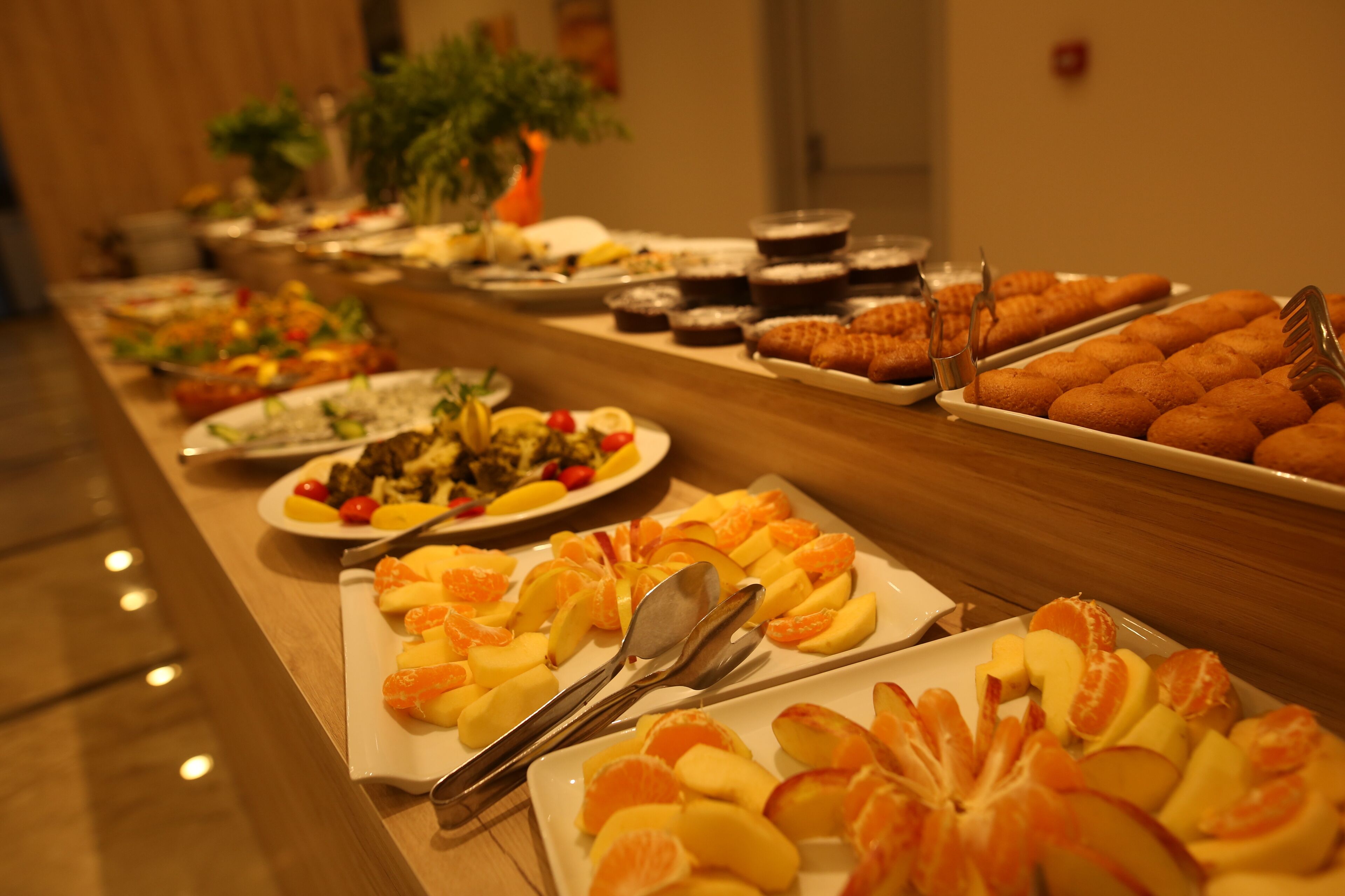 A buffet with various food items including fruits and pastries.