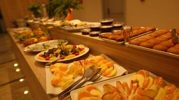 A buffet with various food items including fruits and pastries.
