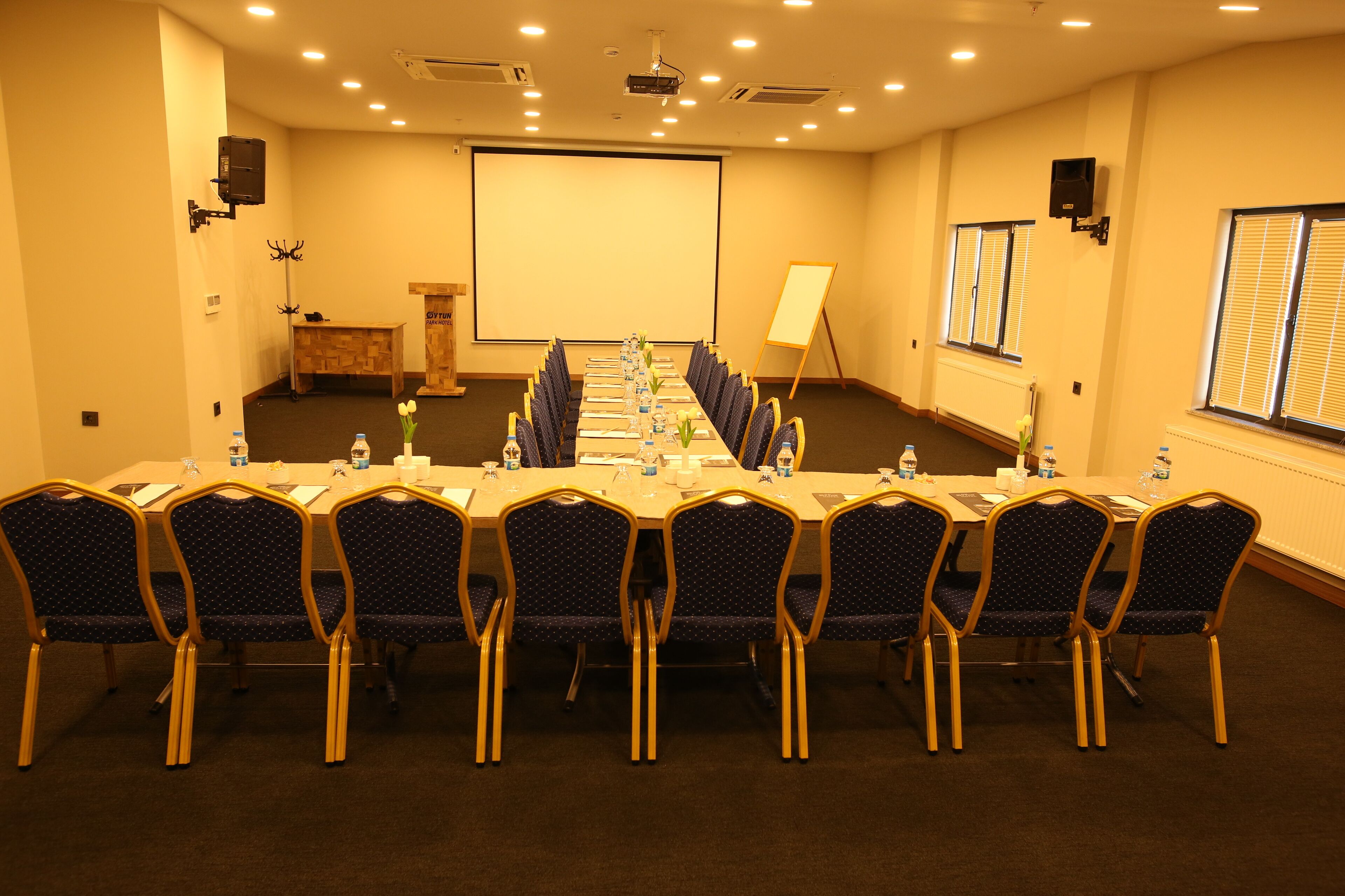 A conference room with a long table, chairs, a projector screen, and a whiteboard.