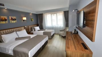 Quarto de hotel com duas camas, uma mesa de trabalho, televisão e obras de arte nas paredes.
