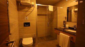 Een moderne badkamer met toilet, een douchecabine van glas, een wastafel met spiegel en een handdoekrek.