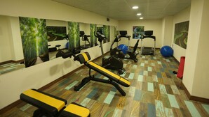 A gym with exercise equipment, mirrors, and artwork on the walls. - Oytun Park Hotel (Çanakkale)