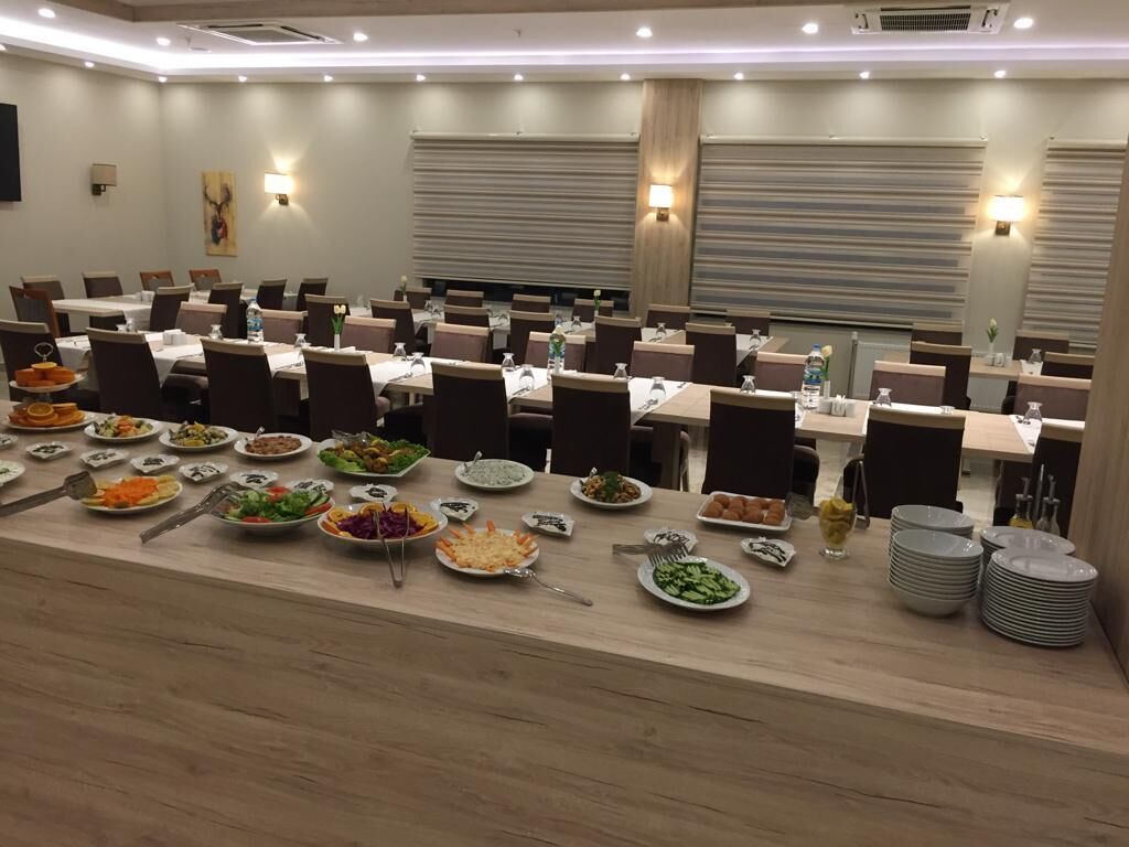 A conference room with multiple tables, each set with plates of food, chairs, and tableware.