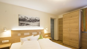 A hotel room with a wooden headboard, a bed with white linens, a nightstand with a lamp, a wardrobe, and a framed picture on the wall. - Tobhartbauer (Dorfgastein)