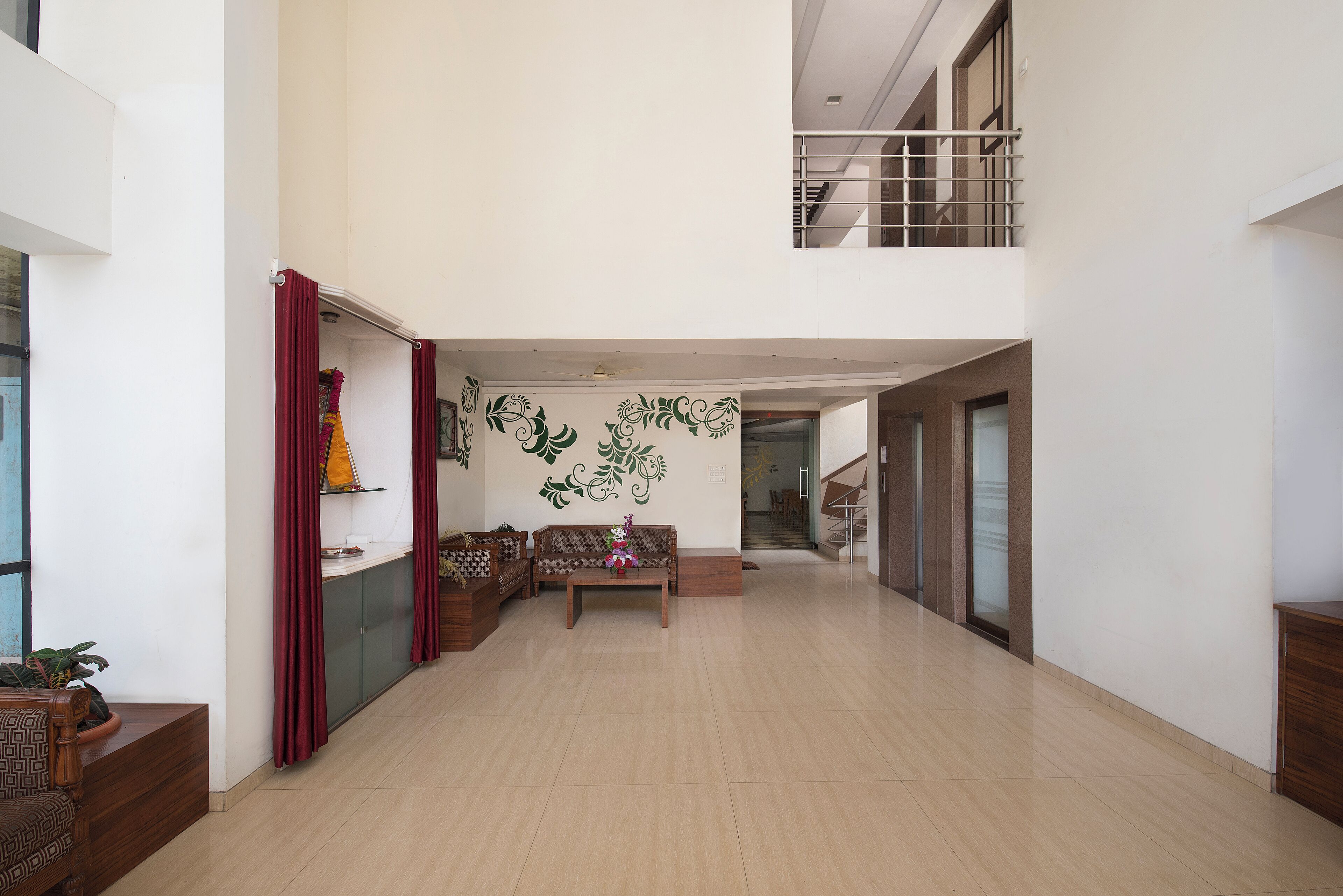 A spacious, well-lit interior with a high ceiling, a central seating area, and a staircase leading to an upper level.