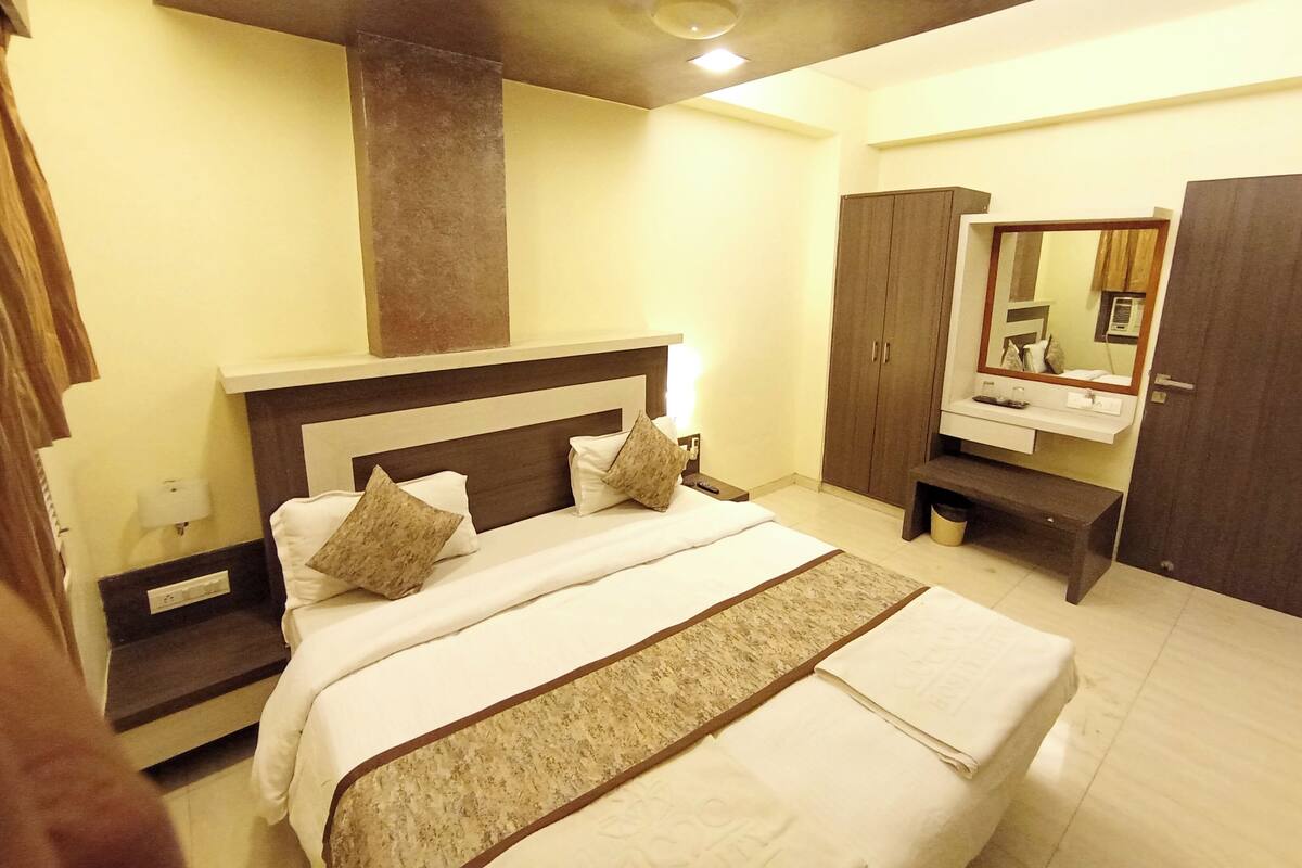 Habitación de hotel con una cama grande, un armario, una tocador con espejo y un ventilador de techo.
