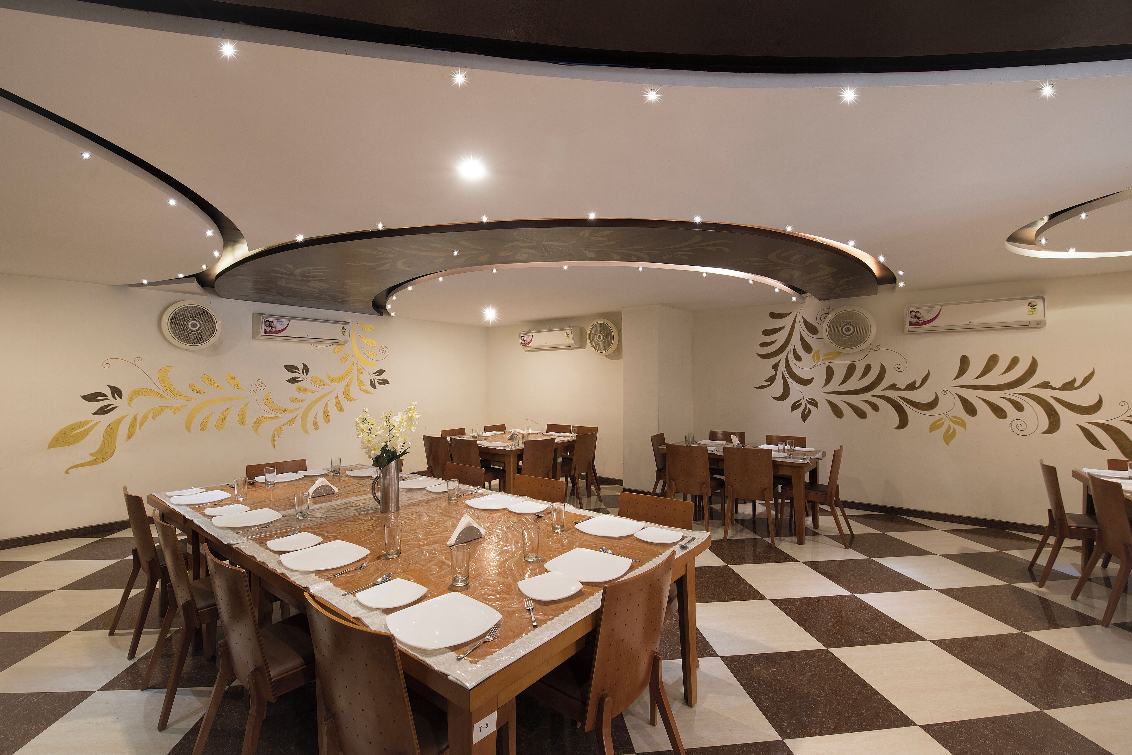 A dining area with a long table set for multiple people, surrounded by chairs, and a patterned floor.